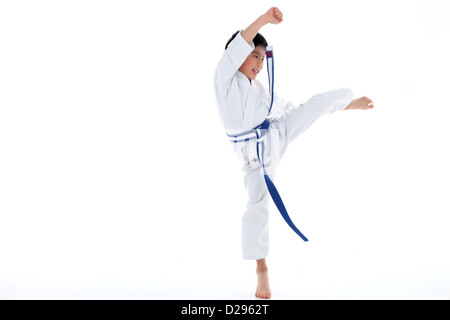 Giovane ragazzo asiatico con nastro blu, Karate calci in aria Foto Stock