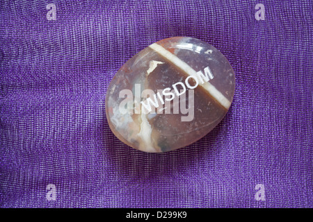 Il commercio equo e solidale sentimento ciottoli - Sapienza pebble isolato su sfondo viola Foto Stock