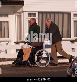 L'uomo spinge una donna anziana in un passeggino Foto Stock
