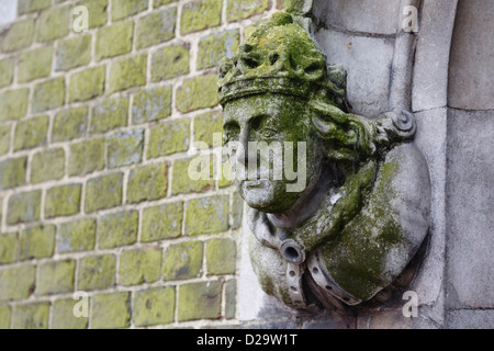 Dettaglio di un edificio storico in Winchester con una pietra scolpita la figura la testa sulla parete Foto Stock