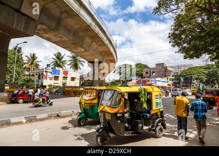 Risciò motorizzati e passare il traffico sotto il recentemente costruito Bangalore metro sopraelevata, Bangalore, India Foto Stock