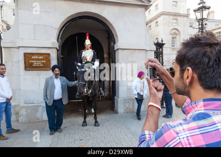 La religione sikh tourist in posa per una fotografia al fianco di un soldato montato del 'Blues e Royals' Cavalleria domestici Horseguards Parade. Foto Stock