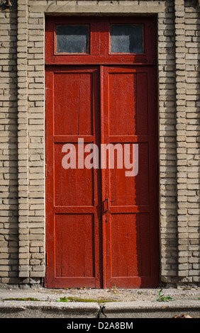 Una vecchia porta di legno rotto con vernice rossa e grunge Foto Stock