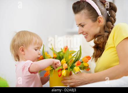 Felice il bambino e la madre facendo decorazione con bouquet di tulipani a benna Foto Stock