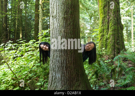 Le donne che spuntavano da dietro tree Foto Stock