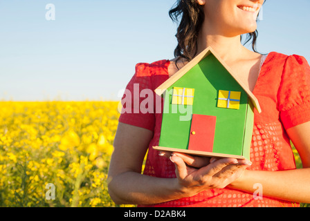 Donna che mantiene modello di casa nel campo Foto Stock