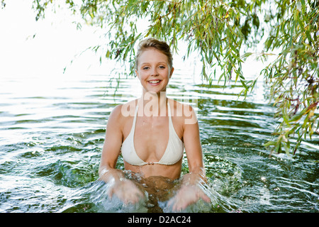 Donna sorridente schizzi in fiume Foto Stock