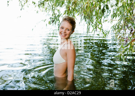 Donna sorridente guadare in fiume Foto Stock