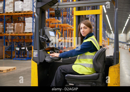 Lavoratore operante il carrello elevatore in magazzino Foto Stock
