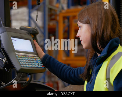 Lavoratore operante il carrello elevatore in magazzino Foto Stock