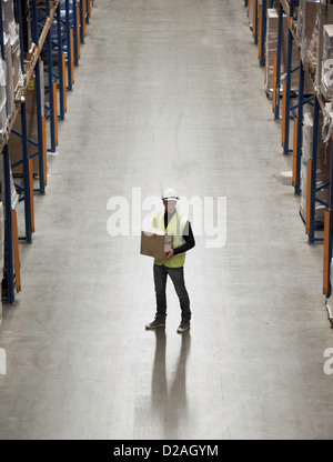 Lavoratore scatola portante in magazzino Foto Stock