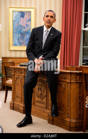 Il Presidente Usa Barack Obama si siede sul bordo della scrivania risoluto durante una riunione in ufficio Ovale della Casa Bianca 19 Dicembre 2012 a Washington, DC. Foto Stock