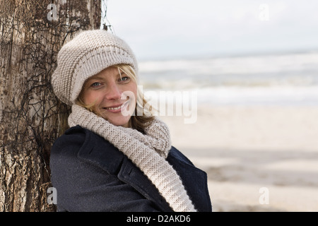 Donna sorridente appoggiato contro log Foto Stock