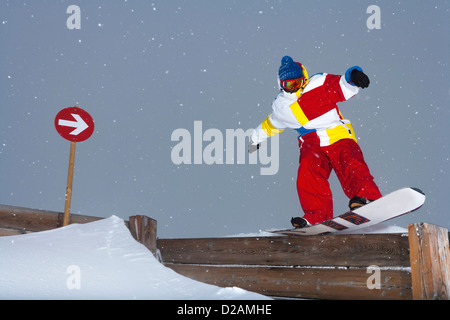 Snowboarder scorrimento sulla recinzione di legno Foto Stock