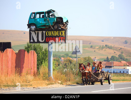 Pullman il passaggio di un segno di traffico con un relitto auto su una strada nella contea di Brasov, Romania Foto Stock