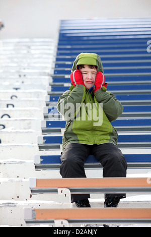 Sconvolto bambino da solo nelle gabbie a uno stadio sportivo Foto Stock