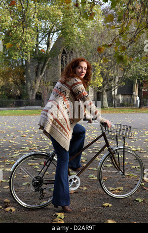 Donna in piedi sulla bicicletta in posizione di parcheggio Foto Stock