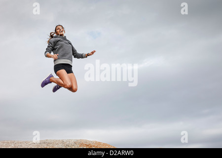 Donna salti di gioia sul boulder Foto Stock