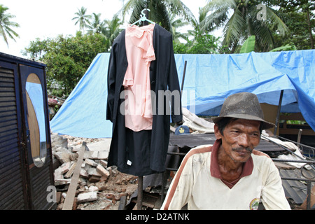 Sungai Rambai, Indonesia, un interessato uomo anziano davanti alla sua casa distrutta Foto Stock