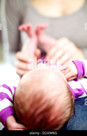 Piccolo neonato sdraiato sul suo giro delle madri con la sua testa verso la telecamera con dof poco profondo Foto Stock