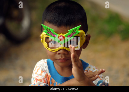 Ragazzo giocando per le strade di Koh Chang Thailandia supereroe che indossa gli occhiali di protezione Foto Stock