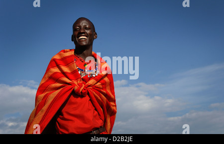 Un giovane guerriero Masai sorge nella riserva Masai Mara, Kenya, Africa orientale, che indossa abiti tradizionali. Foto Stock