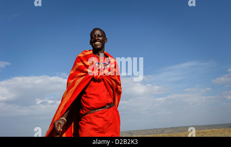 Un giovane guerriero Masai sorge nella riserva Masai Mara, Kenya, Africa orientale, che indossa abiti tradizionali. Foto Stock