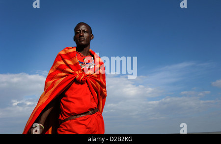 Un giovane guerriero Masai sorge nella riserva Masai Mara, Kenya, Africa orientale, che indossa abiti tradizionali. Foto Stock