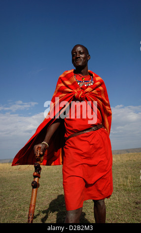 Un giovane guerriero Masai sorge nella riserva Masai Mara, Kenya, Africa orientale, che indossa abiti tradizionali. Foto Stock