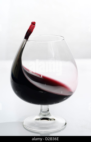 Porta di vorticazione arrivando al punto di un cuore in un bicchiere snifter su sfondo bianco Foto Stock