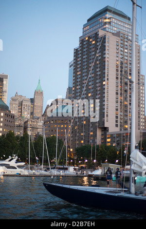 Yacht entra North Cove al crepuscolo con inferiore dello skyline di Manhattan al di là. Foto Stock