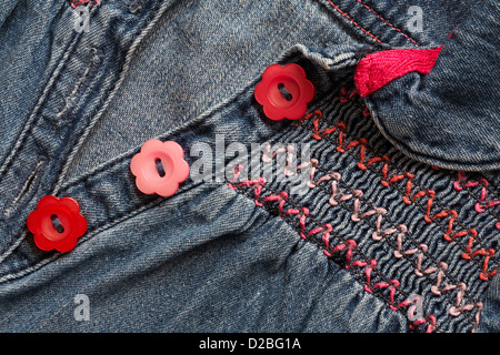 pulsanti a forma di fiori rossi e rosa a margherita e soffocante abito smok in denim per bambina Foto Stock