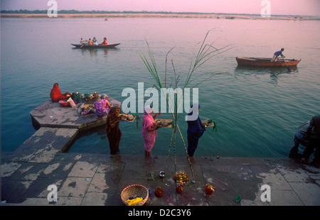 Tre donne indiane facendo Puja preghiere sulle rive del fiume sacro Gange nella città più antica India Banaras ora Varanasi Uttar Pradesh, India. Foto Stock