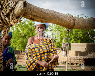 Una donna pause dal prelievo di acqua in corrispondenza di un pozzetto in Diouna, un villaggio agricolo nel sud-est del Mali. Foto Stock