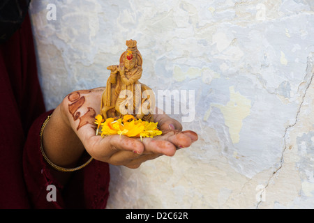 Teenage ragazza indiana tenendo una statua di Krishna statua e petali di fiori. India Foto Stock