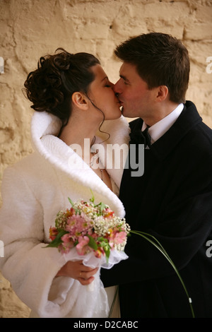 Lo sposo e la sposa bacio sullo sfondo di una parete Foto Stock