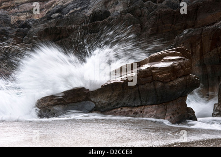 Ondata di schiantarsi contro la roccia sulla spiaggia Foto Stock