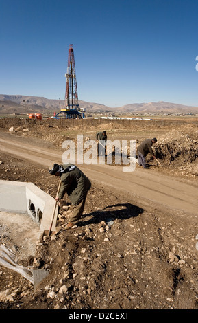 Onshore di esplorazione di petrolio e gas rig sito piattaforma e curdi iracheni dal villaggio locale impiegato per il trasporto su strada e su canale sotterraneo iraq kurdistan Foto Stock