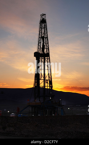 Olio e gas esplorazione onshore rig derrick al tramonto con le montagne dietro. Il Kurdistan iracheno, Iraq settentrionale Foto Stock