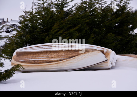 Coperta di neve imbarcazioni a remi recante capovolto sulla neve fresca vicino al bordo delle acque al Piperdam Country Park vicino a Dundee, Regno Unito Foto Stock