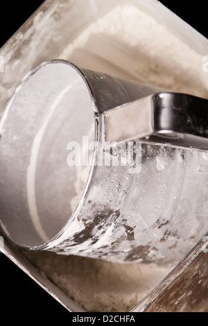 Misurare la tazza di farina nella casella su sfondo nero Foto Stock