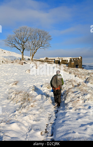 Walker su Pennine Way, Top Withens in inverno la neve su Haworth Moor, Haworth, West Yorkshire, Inghilterra, Regno Unito. Foto Stock