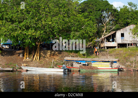 Villaggio sul fiume Rio delle Amazzoni con tradizionali case in legno, barche colorate e lussureggianti dintorni della giungla Foto Stock