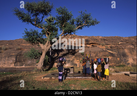 Le donne e i bambini del Mali, Africa Occidentale, raccolta di acqua dal bene. Foto Stock