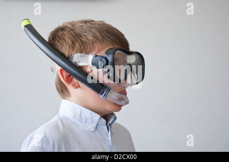 Un ragazzo pronto per andare in vacanza, pone indossando una maglietta con la sua attrezzatura fare snorkeling a. Foto Stock