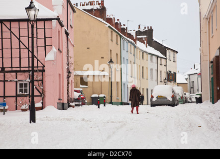 Una donna in Red Hat e pelliccia passeggiate passato edifici storici nella neve Foto Stock