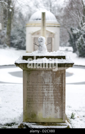 Un piccolo pupazzo di neve sulla parte superiore di un monumento di pietra in Chiswick Park con una iscrizione latina di commemorazione Lilly, un cane. Foto Stock