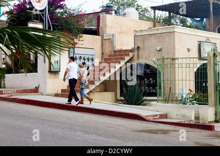 Un paio di passeggiate passato un pittoresco edificio su una strada a Todos Santos, Messico Foto Stock