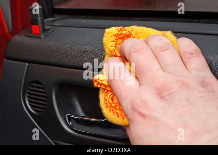 La pulizia della macchina interna porta giallo con un panno per lucidatura Foto Stock