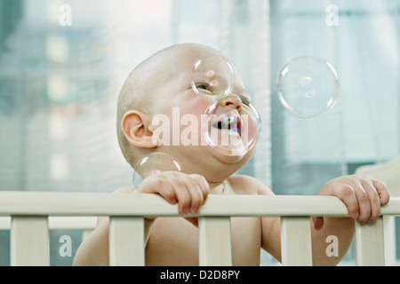 Bambino nella culla godendo le bolle Foto Stock